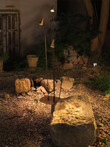 The stems lit on gravel beside a pale rock and a clay garden pot
