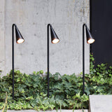 Three stems lit in a row above an ivy filled planter on a wall