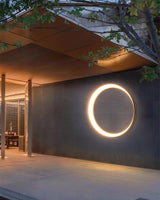 The ring lit on a wall of a courtyard under a wood canopy beside a glass door