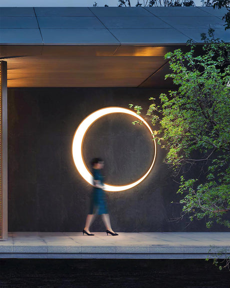 The lit ring on a dark wall of a covered walkway, a person walking past