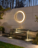 The ring lit on a garden wall above a stepped water feature and a lawn
