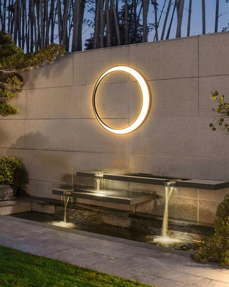The ring lit on a garden wall above a stepped water feature and a lawn