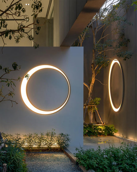 Two rings lit on facing garden walls above a planted bed and trees
