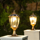 Two bronze lanterns lit on low pillars beside a planted garden path