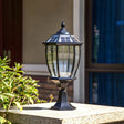 The lantern lit on a pillar with planting and a blue door behind it