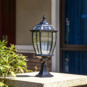 The lantern lit on a pillar with planting and a blue door behind it