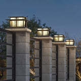 A row of caps lit along tall pillars beside a driveway at night