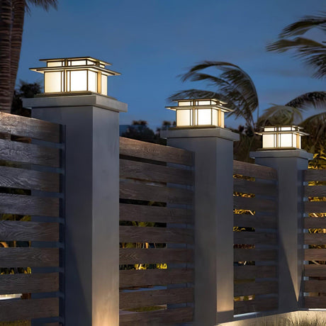 Caps lit on stone pillars with palms and a lit house behind them