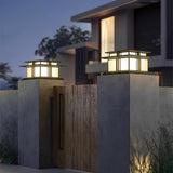 A pair lit on concrete gate pillars either side of a timber gate at dusk