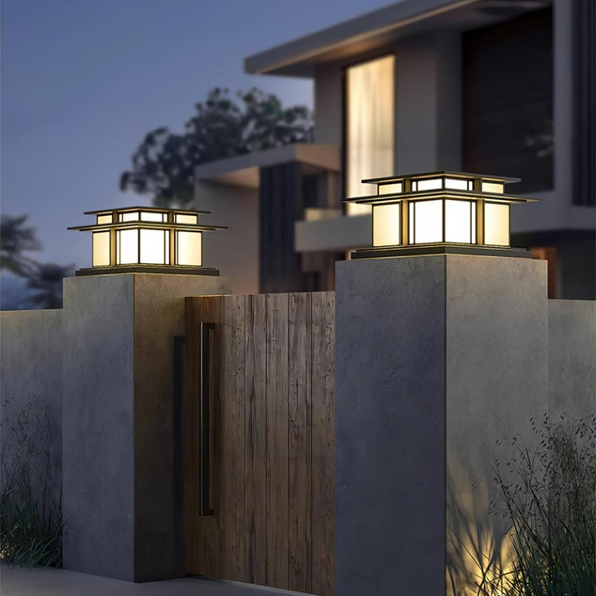 A pair lit on concrete gate pillars either side of a timber gate at dusk