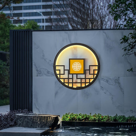 The light on a marble clad wall above a planted pond edge