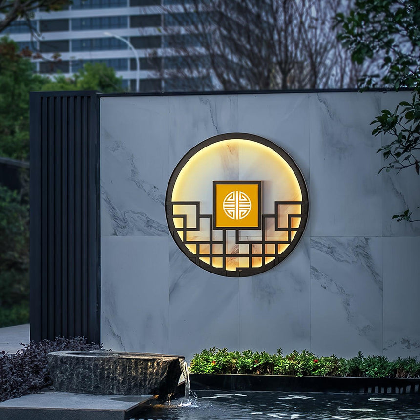 The light on a marble clad wall above a planted pond edge