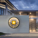 The round light on a terrace wall above lit outdoor steps, a modern house behind