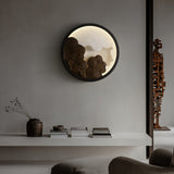 Sconce lit above a long console beside a low sofa and a stone vase