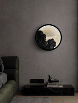 Sconce lit above a green sofa beside a low console stacked with books