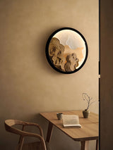 Sconce lit above a wood table with an open book and a pale chair