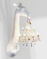 Side view of the white giraffe and the crystal chandelier hanging from its mouth