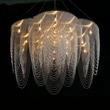 Overlapping steel petal discs above draped curtains of fine chain, lit warm