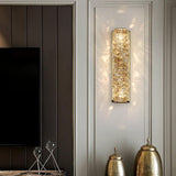The gold version lit on a paneled wall beside a TV and two tall vases in a living room