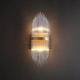 The sconce lit on a dark wall, the rods catching the light