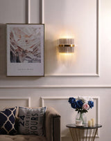 The sconce on a white paneled wall above a sofa and a small side table with roses