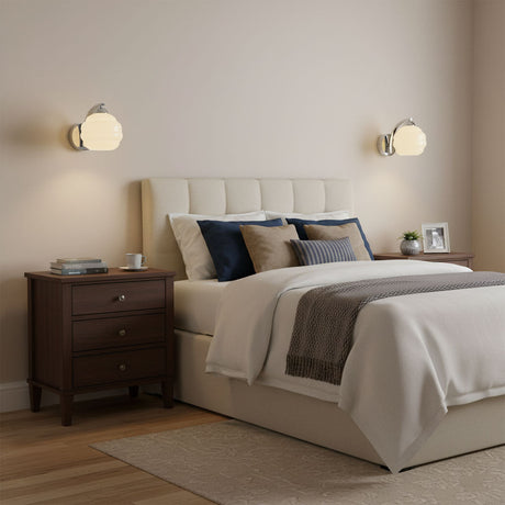 Two sconces lit above wood nightstands in a bedroom with a tufted headboard