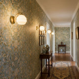 A row of gold sconces lit along a hallway with patterned wallpaper and a runner