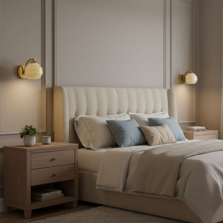 A pair of sconces lit on either side of an upholstered headboard