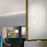 Opal glass balls lit in a row above a bar counter and shelves