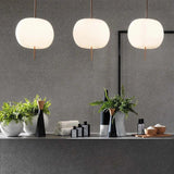 Three opal glass balls lit above a dark counter with vases on it