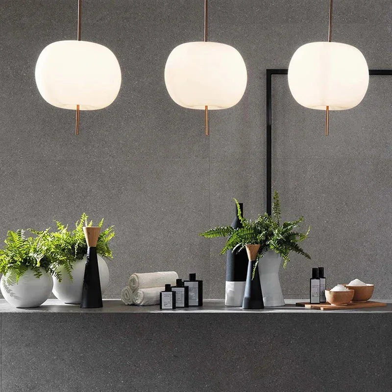 Three opal glass balls lit above a dark counter with vases on it
