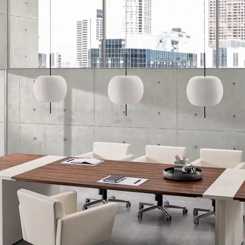 Three opal glass balls lit above a long table with pale chairs