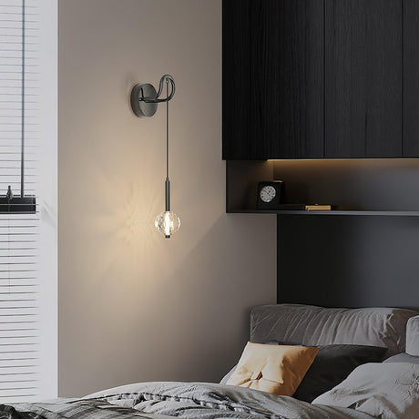 The crystal ball lit above a bed with gray linens beside dark wood cabinets
