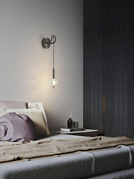 The crystal ball lit beside a dark wood wall above a bed with a purple pillow