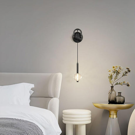 The crystal ball lit above a gold nightstand with flowers beside a white bed