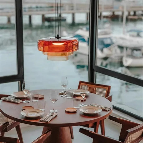 Orange stacked glass shade above a round table by a marina window