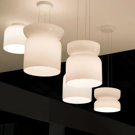 Cluster of four white glass shapes hung together against a dark wall