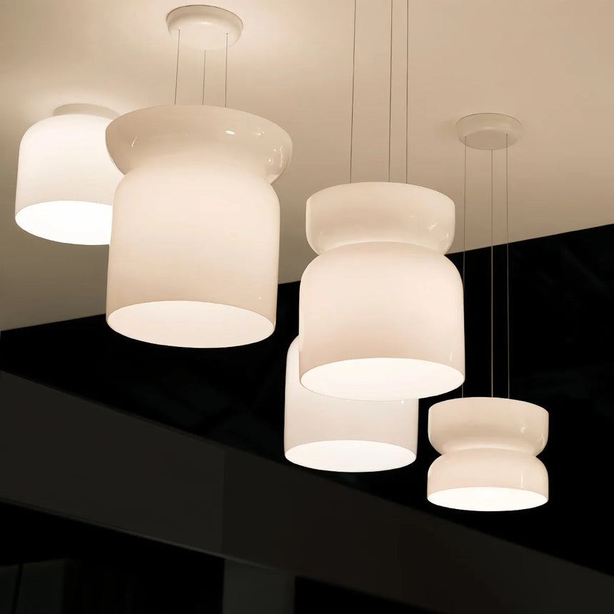 Cluster of four white glass shapes hung together against a dark wall