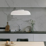 Low white glass shade hung in front of a marble kitchen backsplash