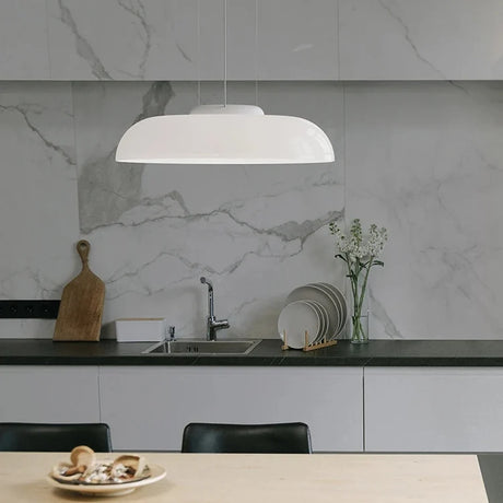 Low white glass shade hung in front of a marble kitchen backsplash