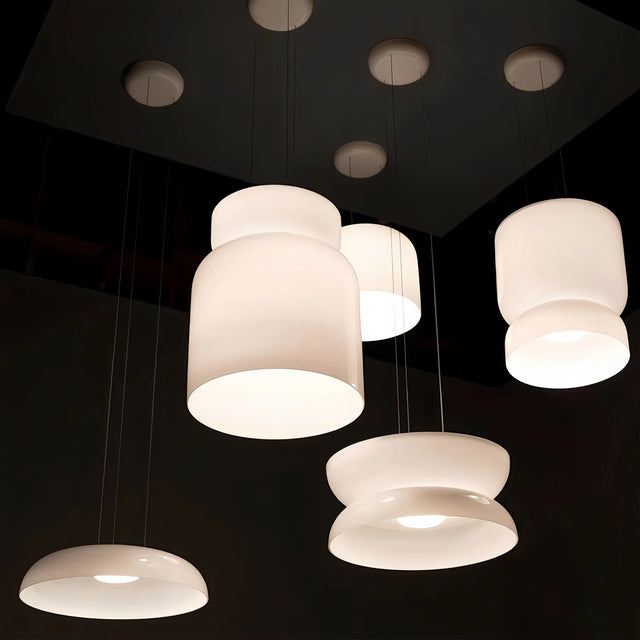 Glass pendant light in white jade glass, several shapes hung together on a dark ceiling