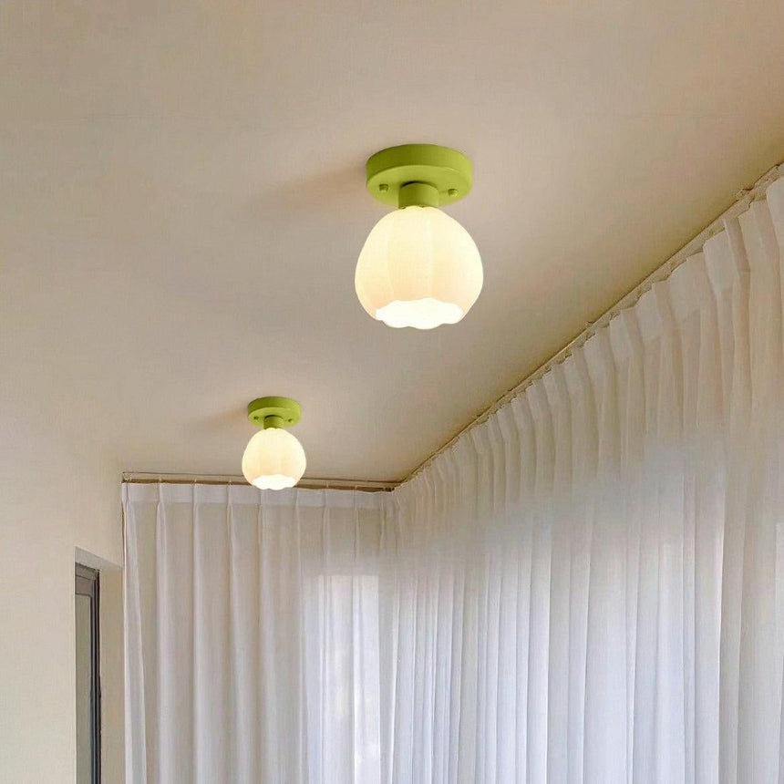 Two flower shade ceiling lights lit along a hallway ceiling beside curtains
