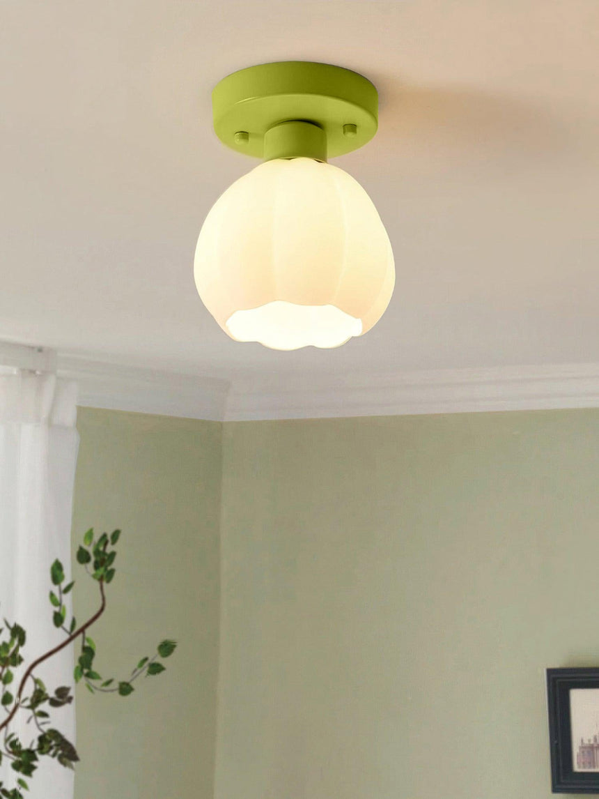 Flower shade ceiling light lit on a white ceiling in a room with a green wall