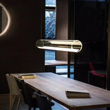 The tube above a wooden dining table in a dark room with a window