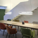 Two tubes lit in a row above a long meeting table with coloured chairs