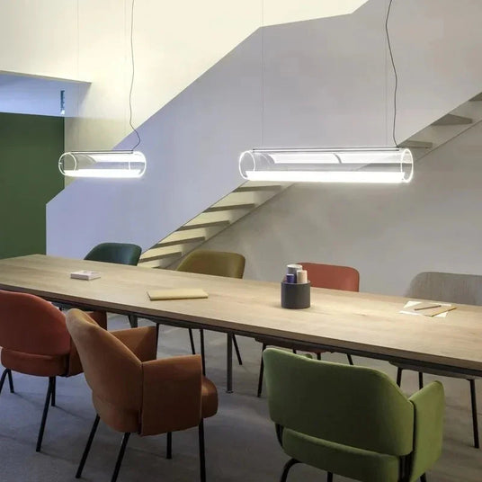 Two tubes lit in a row above a long meeting table with coloured chairs