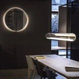 The tube seen across a room beside a lit ring artwork on a dark wall