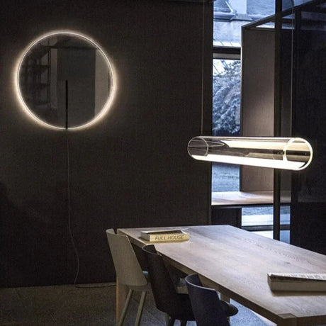 The tube seen across a room beside a lit ring artwork on a dark wall