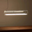 A horizontal glass tube lit above a pale table in a warm toned room