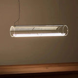 A horizontal glass tube lit above a pale table in a warm toned room